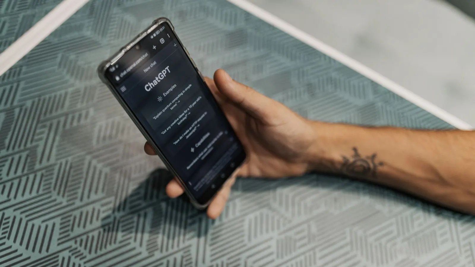 A hand holding a smartphone with the ChatGPT app open on screen