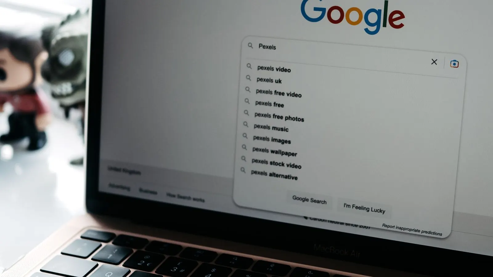 A laptop screen showing a Google search box with a list of suggested searches